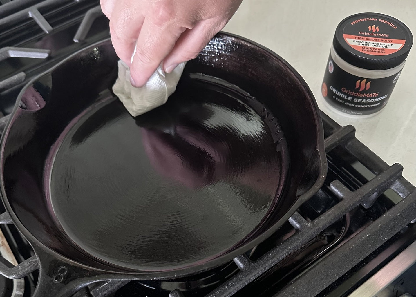 GriddleMATe seasoning being applied to a hot cast iron pan to season, condition, and maintain surface.
